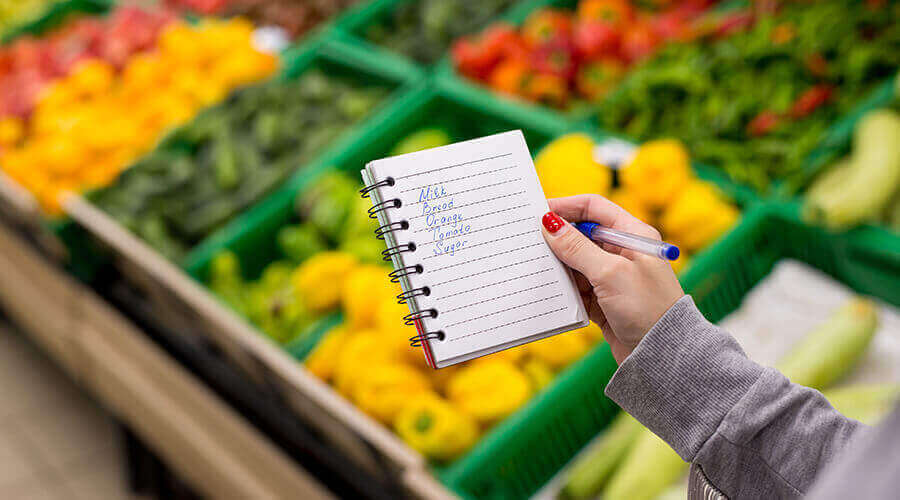 A home care worker reviews a grocery list in the produce aisle.