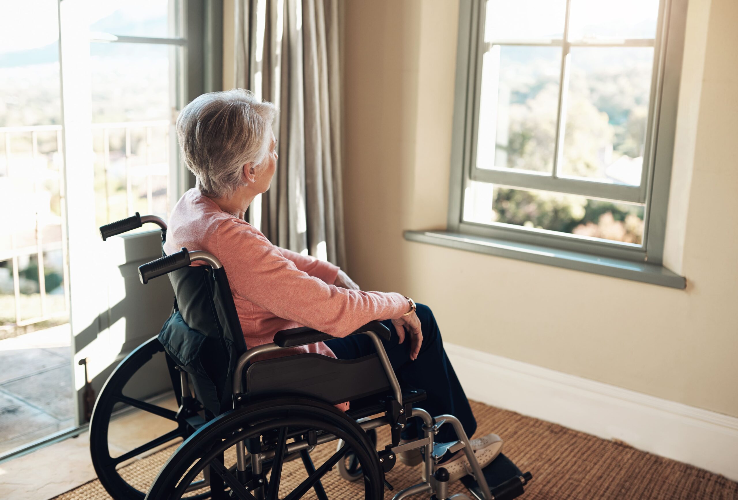 an older woman in a wheelchair sits alone after losing a caregiver